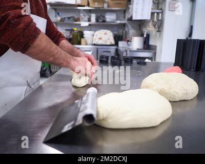 bäckerkoch, der rot-violett-gelb und grün kleine 30 Gramm farbige Brötchen für Fingerfood für Veranstaltungen macht - Catering-Zubereitung Stockfoto