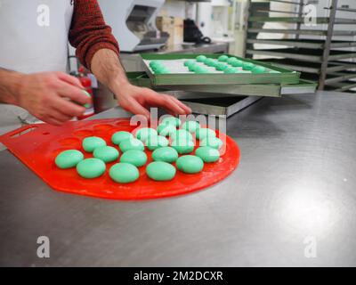 bäckerkoch, der rot-violett-gelb und grün kleine 30 Gramm farbige Brötchen für Fingerfood für Veranstaltungen macht - Catering-Zubereitung Stockfoto