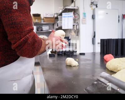 bäckerkoch, der rot-violett-gelb und grün kleine 30 Gramm farbige Brötchen für Fingerfood für Veranstaltungen macht - Catering-Zubereitung Stockfoto