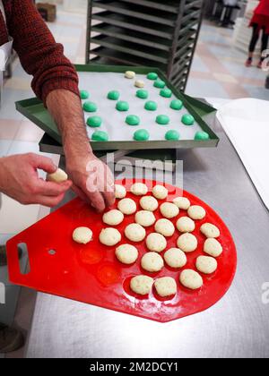 bäckerkoch, der rot-violett-gelb und grün kleine 30 Gramm farbige Brötchen für Fingerfood für Veranstaltungen macht - Catering-Zubereitung Stockfoto