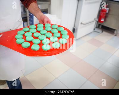 bäckerkoch, der rot-violett-gelb und grün kleine 30 Gramm farbige Brötchen für Fingerfood für Veranstaltungen macht - Catering-Zubereitung Stockfoto