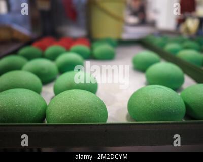 bäckerkoch, der rot-violett-gelb und grün kleine 30 Gramm farbige Brötchen für Fingerfood für Veranstaltungen macht - Catering-Zubereitung Stockfoto