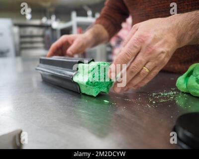 bäckermeister schneidet in der Gastronomieküche rote violettgelbe und grüne Sterne und herzförmige Buns Stockfoto