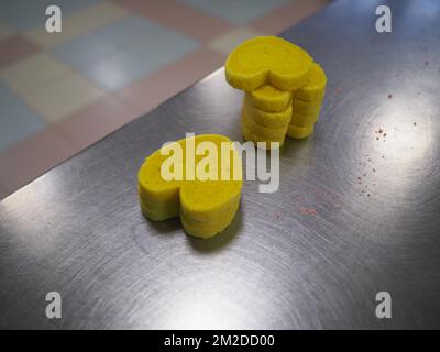 bäckermeister schneidet in der Gastronomieküche rote violettgelbe und grüne Sterne und herzförmige Buns Stockfoto