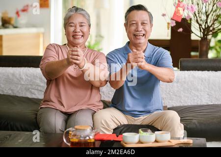 Glücklicher Senior-Mann und glückliche Frau, die Grußgeste machen und vor der Kamera lächeln Stockfoto