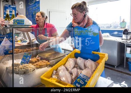 Female fishmongers / vendors selling fresh fish on display at the open-air fish market / Vistrap in the city Ostend / Oostende, Belgium | Poissonnerie / marché au poisson au Vistrap sur le quai du port d'Ostende, Belgique 19/04/2018 Stock Photo