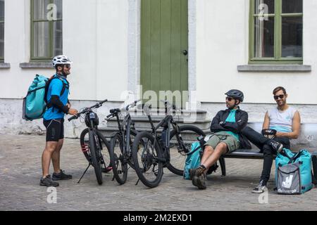 Fahrradkuriere - arbeiten für Deliveroo, britisches Online-Lebensmittellieferunternehmen - eine Pause im Stadtzentrum | Coursiers à vélo de Deliveroo, Service de livraison de plats cuisinés à Gand, Belgique 03/05/2018 Stockfoto