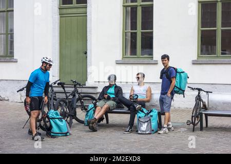 Fahrradkuriere - arbeiten für Deliveroo, britisches Online-Lebensmittellieferunternehmen - eine Pause im Stadtzentrum | Coursiers à vélo de Deliveroo, Service de livraison de plats cuisinés à Gand, Belgique 03/05/2018 Stockfoto