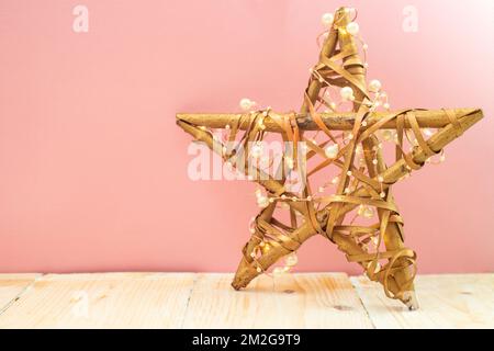 Zweige oder Zweige, Stern, handgefertigt, mit weihnachtslichtern auf pinkfarbenem Hintergrund Stockfoto