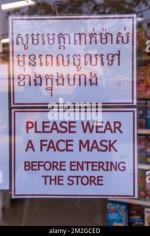 Während der COVID-19-Pandemie ist in einem Supermarkt ein zweisprachiges Schild mit der Aufschrift „Bitte tragen Sie eine Gesichtsmaske“ zu sehen. Phnom Penh, Kambodscha. © Kraig Stockfoto