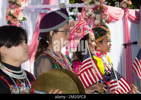 Die Hmong-Jugend trägt in traditioneller Kleidung amerikanische Flaggen bei der Hmong-Neujahrsfeier im El Dorado Park in Long Beach, Kalifornien Stockfoto