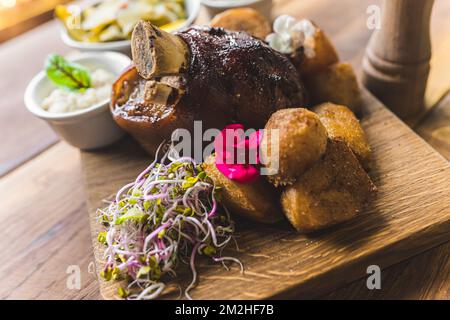 Traditionelle polnische Küche - golonka: In moderner Weise geröstetes Schweinefleisch mit knusprigen, im Ofen gebackenen Kartoffeln und Bohnensprossen. Hochwertiges Foto Stockfoto