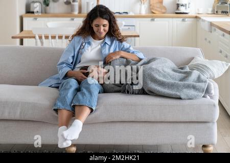 Tired child daughter covered with warm blanket fall asleep after school, sleeping on mother knees Stock Photo