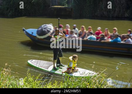 Boat with tourists passing man with child on stand up paddle board / SUP in the city Mechelen / Malines, Antwerp, Flanders, Belgium | Bateau avec touristes et balade par stand up paddle board dans la ville de Malines, Belgique 06/08/2018 Stock Photo