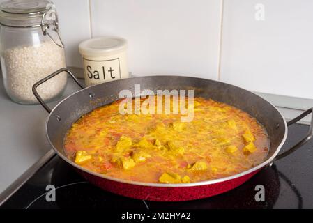 Pfanne für Paellas mit Gemüse, Zutaten und Fleisch, die ohne Zusatz des Reises auf Temperatur gebracht werden. Stockfoto