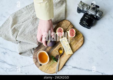 Aus einem großen Blickwinkel können Sie sehen, wie ein Fotograf mit exotischen Früchten und Honig Stille zum Leben erweckt und mit der Kamera fotografiert Stockfoto