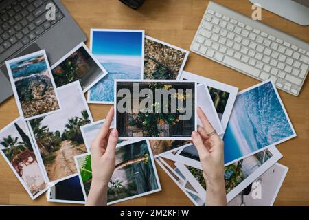 Aus einem großen Blickwinkel betrachtet eine Fotografin ihre professionellen Fotos, während sie mit dem Computer am Arbeitsplatz sitzt Stockfoto