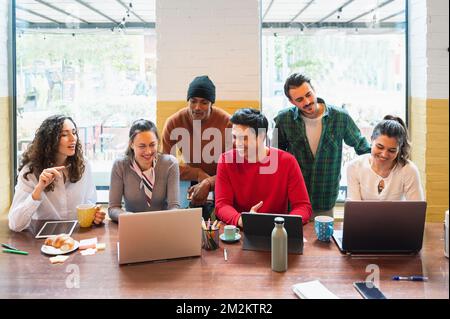 Frontsichtgruppe über junge, multiethnische Menschen mit fröhlichen lächelnden Gesichtern, die in Teamarbeit am Tisch arbeiten. Stockfoto
