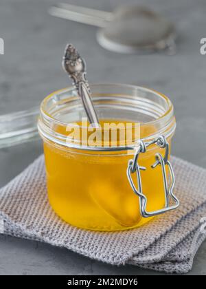 Gesundes hausgemachtes Ghee oder gereinigte Butter in einem Glas auf grauem Betonhintergrund. Gesundes Ayurveda-Lebensmittelkonzept. Stockfoto