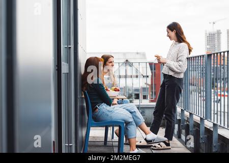 Drei junge Schülerinnen verbringen Zeit auf dem Balkon, machen eine Pause vom Lernen Stockfoto