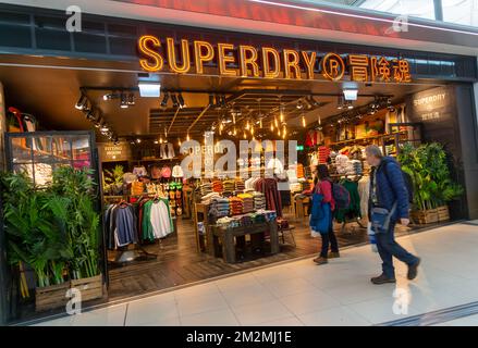 Passagiere, die am Superdry Modegeschäft, Stansted Airport, Essex, England, Großbritannien vorbeilaufen Stockfoto