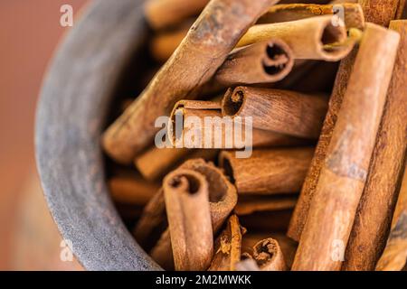 Holzschüssel, Draufsicht mit Zimtstäbchen auf dunklem Holzhintergrund. Abstrakte Lebensmittel und Kochzutaten für Dessert und gesunde Mahlzeiten Stockfoto