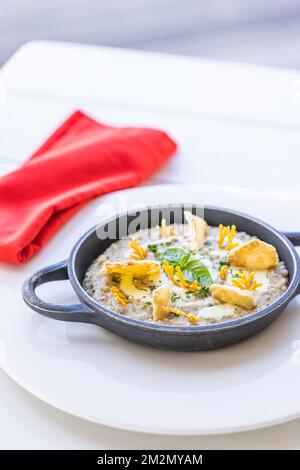 Wunderschönes und leckeres Essen auf einem Teller. Gourmetgericht auf weißem Tisch mit roter Serviette, luxuriöses Hotelresort-Spezialgericht. Trüffelpilze und Gemüse Stockfoto