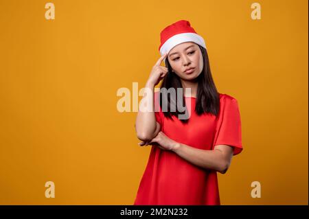 Die hübsche junge Frau und der weihnachtsmann-Hut sehen aufmerksam aus Stockfoto