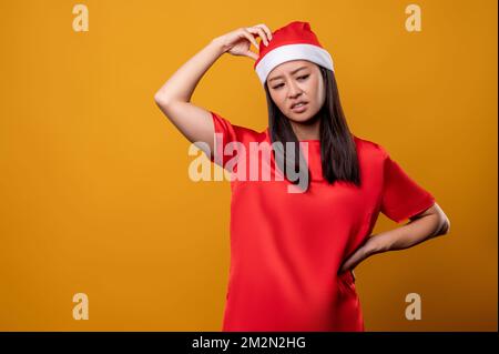 Die hübsche junge Frau und der weihnachtsmann-Hut sehen aufmerksam aus Stockfoto