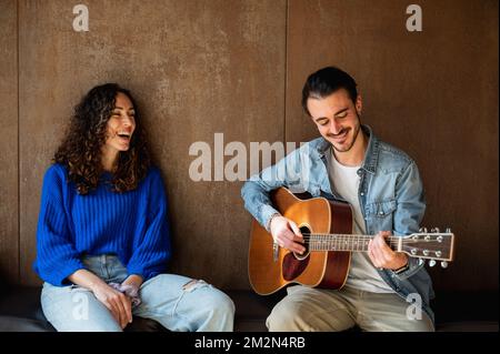 Hübsches, weißes, junges Paar, das Gitarre spielt und singt Stockfoto