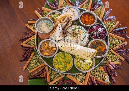 Typisch indisches Thali. Vegetarische Gerichte auf einem großen runden Teller. Indisches Essen, sambar, appam, Semolina Halwa, upma serviert auf Bananenblättern Stockfoto
