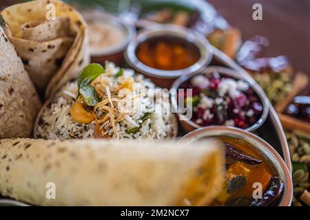 Typisch indisches Thali. Vegetarische Gerichte auf einem großen runden Teller. Indisches Essen, sambar, appam, Semolina Halwa, upma serviert auf Bananenblättern Stockfoto