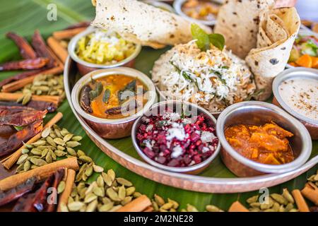 Typisch indisches Thali. Vegetarische Gerichte auf einem großen runden Teller. Indisches Essen, sambar, appam, Semolina Halwa, upma serviert auf Bananenblättern Stockfoto