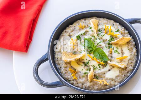 Wunderschönes und leckeres Essen auf einem Teller. Gourmetgericht auf weißem Tisch mit roter Serviette, luxuriöses Hotelresort-Spezialgericht. Trüffelpilze und Gemüse Stockfoto