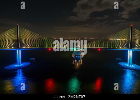 Panoramablick über die Sunshine Skyway Bridge über Tampa Bay mit vorbeifahrendem Schiff bei Nacht Stockfoto
