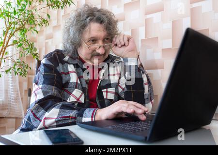 Ein älterer Mann mit schlechtem Sehvermögen, der am Computer arbeitet, eine Nahaufnahme Stockfoto