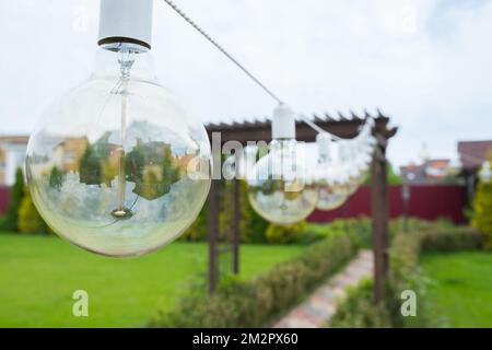 Nahaufnahme einer Glühlampe, die im Garten hängt Stockfoto