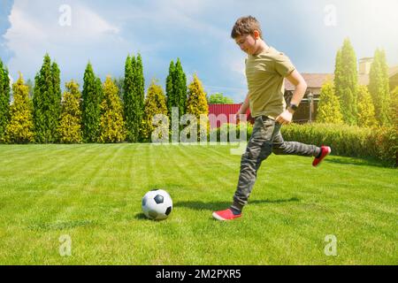 Ein 11-jähriger Teenager spielt Fußball im Hinterhof des Hauses. Sportlicher Lifestyle Stockfoto