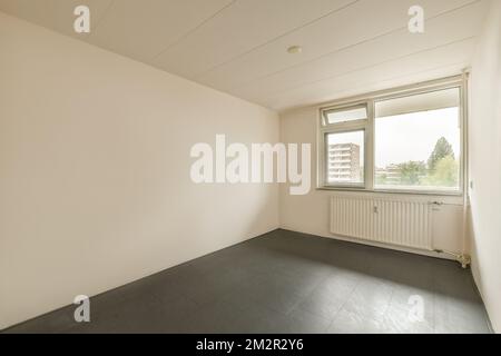 an empty room with white walls and black tiles on the floor there is a large window in the corner that looks out to the Stock Photo