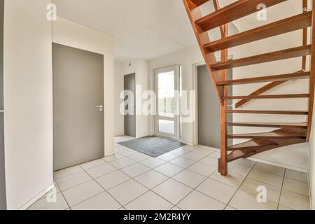 Ein leeres Zimmer mit Treppen und Fliesenboden in der Mitte des Zimmers, es gibt eine Treppe, die zum zweiten Stock führt Stockfoto