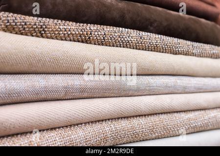 Stapel von gefalteten bunten Textilien. Haufen Stoff braun und beige Farbe Stoff Stockfoto