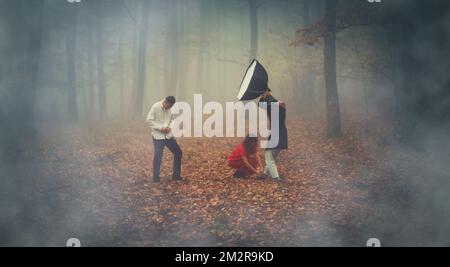 Fotografieren Sie Menschen in einem wunderschönen nebligen Wald, das Foto beinhaltet auch einen Assistenten mit einem blitzschnellen, herbstlichen Buchenwald im Nebel. Stockfoto