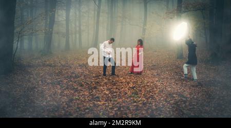 Fotografieren Sie Menschen in einem wunderschönen nebligen Wald, das Foto beinhaltet auch einen Assistenten mit einem blitzschnellen, herbstlichen Buchenwald im Nebel. Stockfoto