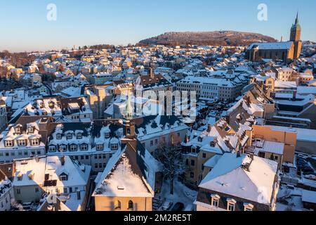 Annaberg Buchholz, Deutschland. 13.. Dezember 2022. Blick auf die winterliche Bergstadt Annaberg-Buchholz mit dem Weihnachtsmarkt und St. Annes Kirche. Bis Dezember 23 bieten mehr als 70 Verkaufsstände unter anderem Glühwein, geröstete Mandeln und Holzkunst aus dem Erzgebirge. Nach Angaben der Stadt hat der Weihnachtsmarkt in der Vergangenheit jedes Mal schätzungsweise 120.000 bis 140.000 Besucher angezogen. (Luftaufnahme mit Drohne) Kredit: Jan Woitas/dpa/Alamy Live News Stockfoto