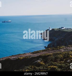 Ein Luftblick auf die Howth Head Halbinsel mit Baily Leuchtturm und Schiff in der Ferne Stockfoto