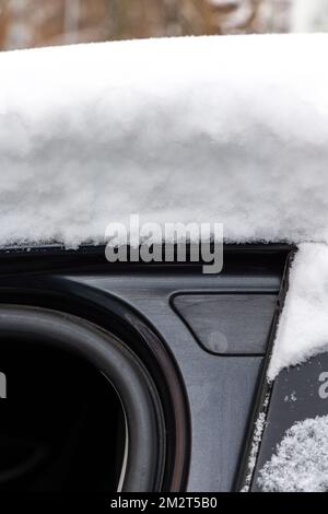 Eine dicke Schicht frischen Schnees auf dem Dach eines Pkw. Starker Schneefall erschwert Fahrern das Leben. Stockfoto