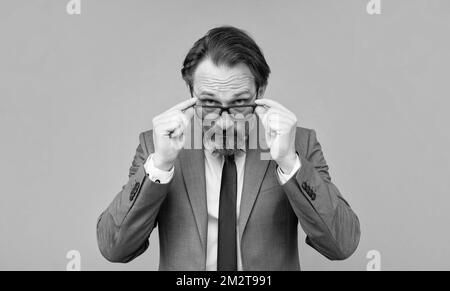 Älterer Mann in Brille sieht auf grauem Hintergrund aus, Augenlicht Stockfoto