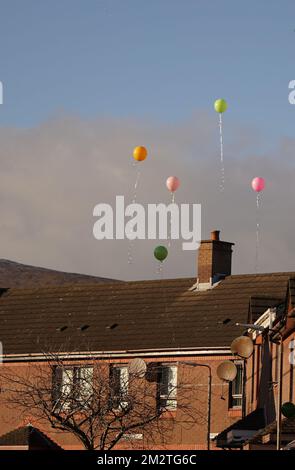 Die Trauernden lassen bunte Heliumballons los, während die Bestattungsgesellschaft von Stella-Lily McCorkindale vor ihrer Beerdigung das Haus ihrer Großmutter in Belfast verlässt. Die fünfjährige Stella-Lily starb, nachdem ein Fall von Strep A in der Grundschule, die sie besuchte, gemeldet wurde. Bilddatum: Mittwoch, 14. Dezember 2022. Stockfoto