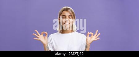 Friedlich ruhig gut aussehende weibliche Blondine in weißen T-Shirt Augen schließen Lächelnd erleichtert und glücklich Gefühl zufrieden mit dem Leben im Stehen lotus-Pose Stockfoto