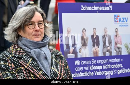 Erfurt, Germany. 14th Dec, 2022. Heike Werner (Die Linke), Minister of Labor, Social Affairs, Health Women and Family of Thuringia, stands on the sidelines of a rally of doctors and pharmacists in front of the Thuringian state parliament. Professional associations of general practitioners, dentists and pharmacists have called for the rally before the state parliament session. 500 participants are registered. The doctors are demanding appropriate compensation for inflation and better appreciation of their work. Credit: Martin Schutt/dpa/Alamy Live News Stockfoto